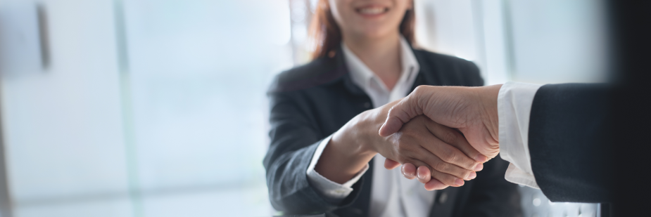 Imagem aproximada de um aperto de mão entre um homem e uma mulher em uma entrevista de emprego. Sinais para ficar alerta.