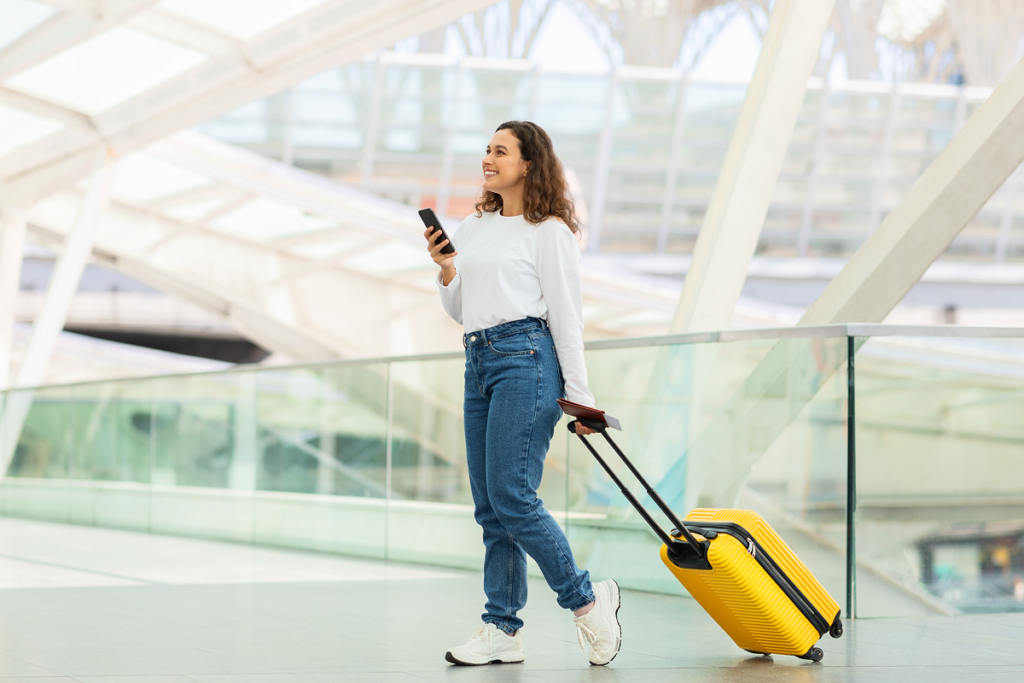 Mulher no aeroporto carregando uma mala. A importância do inglês nos dias atuais.